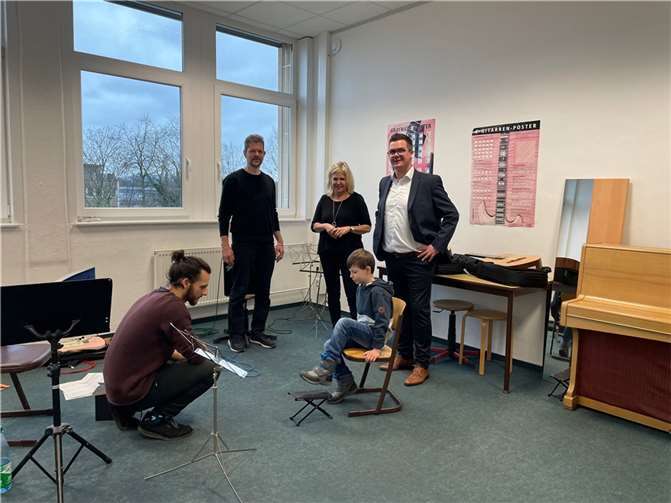Gitarrenlehrer Tim Beckmann (links) zeigte unter anderem beim Tag der offenen Tür der Musikschule Interessierten, worauf es beim Gitarrenspielen ankommt. Das schauten sich ebenfalls Musikschulleiter Martin Geiger (2. v. links), vhs-Leiterin Jutta Günther (Mitte) und Bürgermeister Peter Jung (rechts) an. Foto: Stadt Neuwied