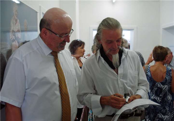 Gregor Bendel signiert einen Katalog für den Bürgermeister.