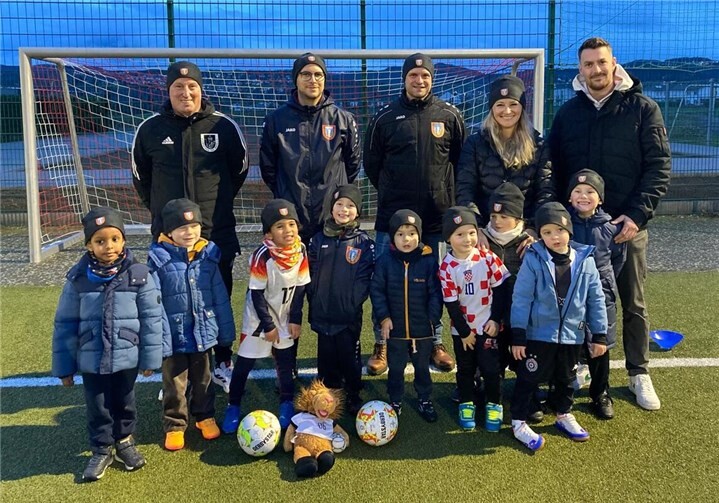 Große Freude bei der Fußballjugend: Ein Teil unserer jüngsten Nachwuchstalente mit den Sponsoren der Fleece-Mützen, Natalia Schwarz (2. v. r.) und Jan Nachtsheim (1. v. r.), sowie Vereinsvertretern. Foto: SV Kripp