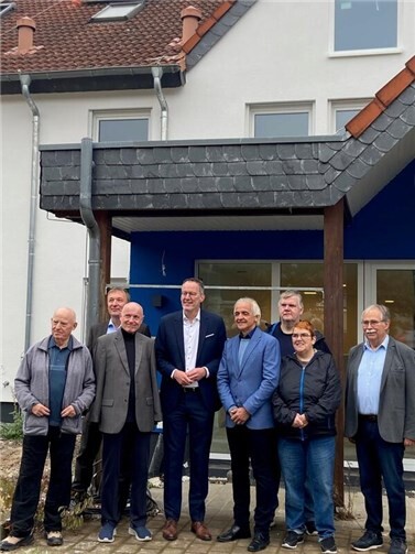Große Freude bei der Lebenshilfe, als Innenminister Michael Ebling (4. von links) den Förderbescheid an die Vertreter der Lebenshilfe und der Stadt Sinzig übergibt. Mit dabei auch Altbürgermeister Norbert Hesch (links), der die Lebenshilfe bei der Suche nach einem Standort für ein neues Lebenshilfehaus intensiv unterstützt. Im Hintergrund das seinerzeit von der Ahr überflutete Lebenshilfehaus in der Pestalozzistraße, das derzeit renoviert wird. Foto: Alexander Beier