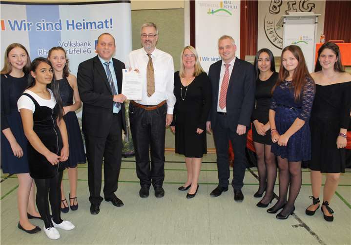 Große Freude herrschte bei den Beteiligten über die offizielle Förderzusage durch das Ministerium für Soziales, Arbeit, Gesundheit und Demografie Rheinland-Pfalz (v.li.) Bürgermeister Johannes Bell, Jobfux Klemens Walter, Konrektorin Andrea Lilienthal, Schulleiter Timo Djelassi mit Schülerinnen des Projektes Jobfux.Privat