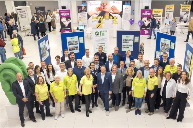 Gruppenfoto anlässlich der Eröffnung des 12. Koblenzer Patiententages 2024, Bildmitte: Der wissenschaftliche Leiter Prof. Dr. Steffen Kreikemeier (Hochschule Aalen) neben Brigitte Hilgert-Becker (Vors. Treffpunkt Ohr und Mitglied der Geschäftsführung von BECKER Hörakustik) und Vereinsmitglieder von Treffpunkt Ohr e.V. in gelben Poloshirts. Außerdem im Bild: Dan Hilgert-Becker und Eva Keil-Becker (beide anwesend als Referenten und Mitglieder der Geschäftsführung von BECKER Hörakustik), die wissenschaftlichen Referenten, Industrieaussteller und Mitarbeiter von BECKER Hörakustik.