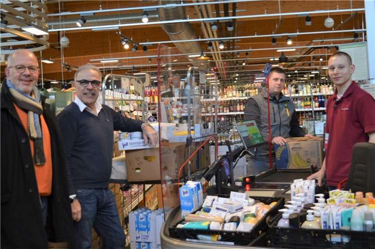 Haltbare Lebensmittel und Hygieneartikel begutachten (von links) Tafelmitarbeiter Ralf Eggert, Inhaber Parviz Azhari vom REWE-Markt Sinzig, Marktleiter Alexander Carrillo und Alexander Schlykow an der Kasse des REWE-Marktes in Sinzig.