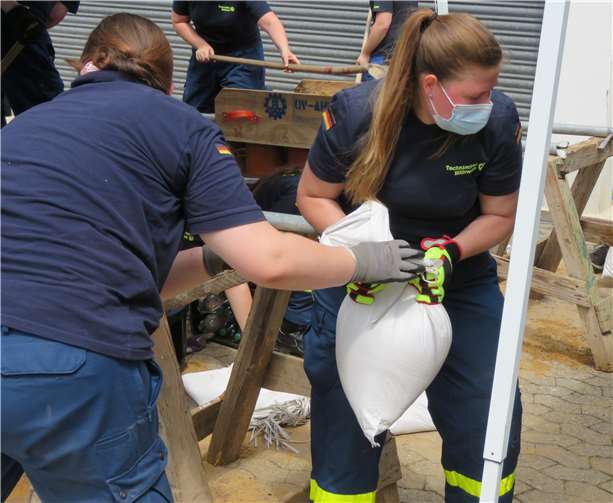 Hand in Hand werden die gefüllten Sandsäcke trotz sommerlichen Temperaturen weitergegeben.