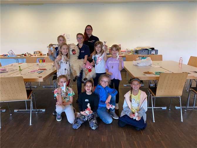 Handpuppenspielerin Eva Grüber (hintere Reihe 2. v. li.) und Lena Kruppa (hintere Reihe re.) vom DRK-Beratungs- und Servicecenter Ahr besuchten mit dem Alpaka Indigo das Feriencamp der OKUJA. Die Kids waren begeistert und schlossen Indigo sofort ins Herz.  Foto: Jule Barth/ OKUJA