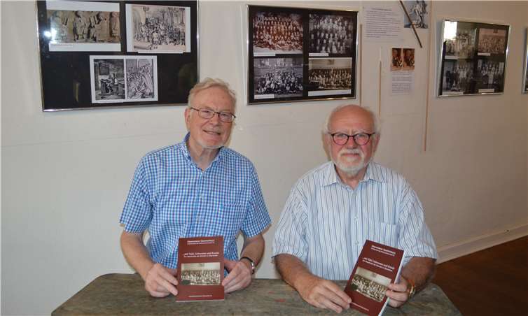Hans Atzler (l.) und Hans Metternich in einer alten Schulbank mit der neuen Schriftenreihe und im Hintergrund die Ausstellung zu den Alten Schulen in Oberwinter. Fotos: AB