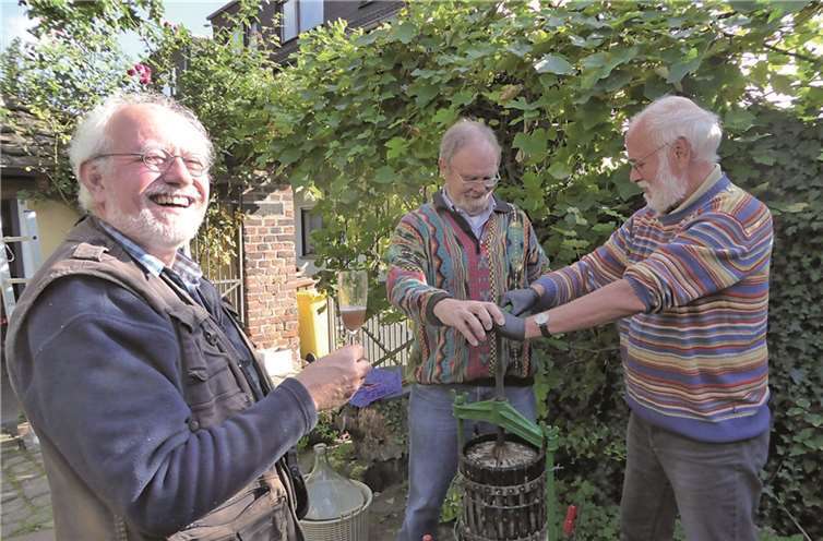 Hans Metternich beim Verkosten des Saftes, an der Kelter v.l. Dr. Heinz Wilms und Prof. Reinhold Viehoff. Privat