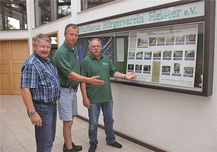 Hans-Willi Euskirchen (v. l.), Knut von Wülfing und Helmut Bürger vor der Fotovitrine, die an den Bau des Bürgerhauses vor 25 Jahren erinnert. STUHA