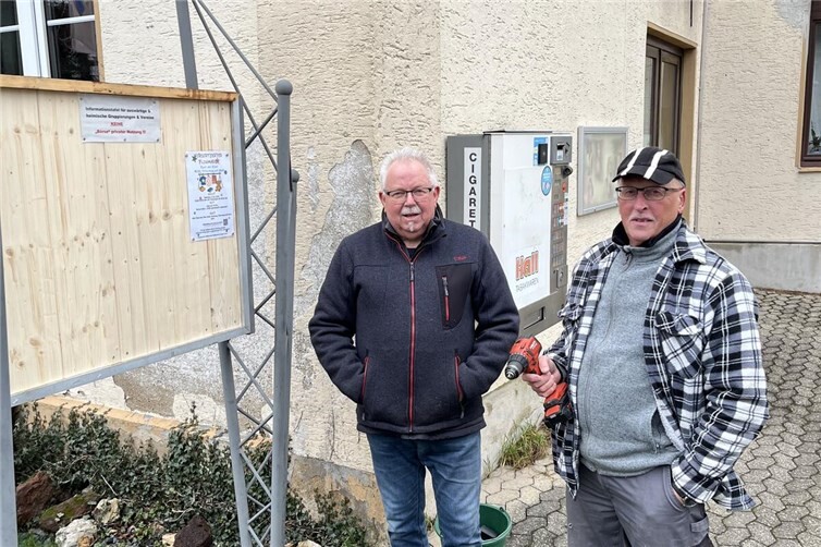 Hans-Willi Jungbluth & Dieter Moog, nach getaner Arbeit und vor den noch zu tätigenden „Verbesserungen“ durch den heimischen Dachdeckerbetrieb Kerp, vor der restaurierten Plakattafel.