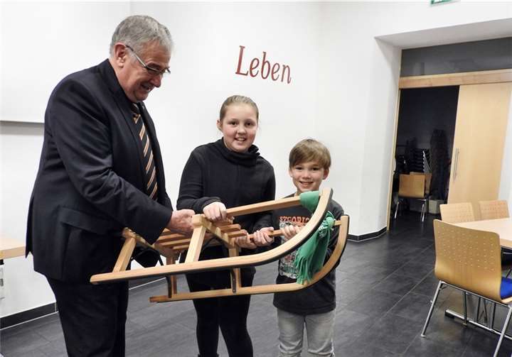 Happy Hauptgewinner Paul Gieler übergibt einen gespendeten Schlitten an Sofia und Killian Knieps.privat