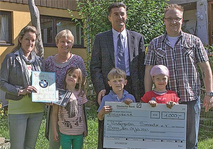 Hauke Mörsch, Leiter der BMW Niederlassung Bonn (Mitte), überreichte einen Spendenscheck über 1000 Euro an die Waldorf-Kindertagesstätte „Sonnentor“ in Heimerzheim. Diesen nahmen zusammen mit den Kindern (v.l.) Physiotherapeutin Carina Pütz, die dienstälteste Erzieherin Elisabeth Frechen und Erzieher Sven Kleebank entgegen. VJ