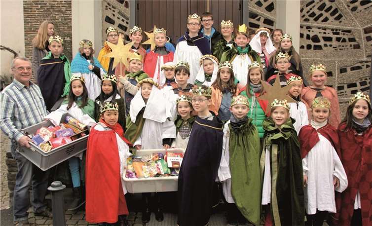 Helmut Krämer (l.), ehrenamtlicher Fahrer der Ahrweiler Tafel, nahm die gesammelten Süßigkeiten von den Dernauer Sternsingern entgegen. CBÜ