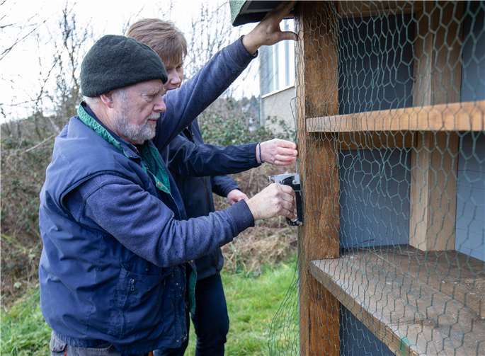 Herbert Riemenschneider und Birgit Wedel versehen die erste Hälfte des Insektenhotels mit einem Vogelschutz.