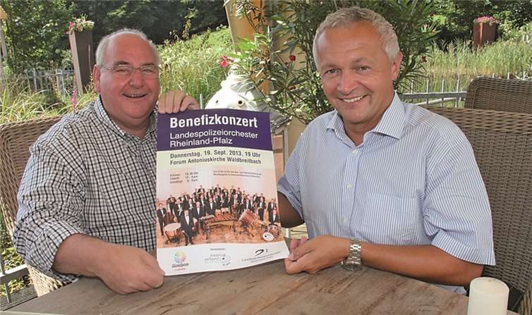 Hermann Josef Esser (links) und Achim Hallerbach stellen das Plakat für das Benefizkonzert des Landespolizeiorchester Rheinland-Pfalz vor.