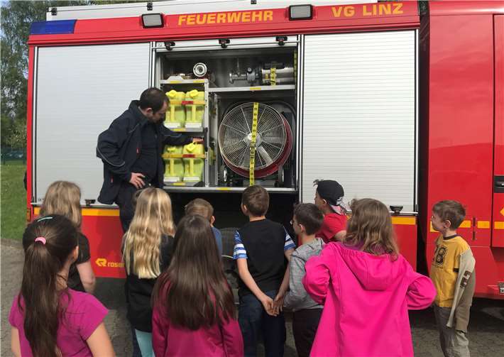 Herr Schaarschmidt, Leiter der Freiwilligen Feuerwehr, mit Schülerinnen und Schülern der Klassen 3a und 3b der Grundschule Sankt Georg.