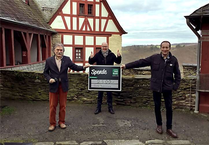 Hoch über dem Rheintal: Auf der Marksburg übergeben Bernd Schittler (Mitte), Vorstandsvorsitzender der PSD Bank Koblenz, und Guido Nördershäuser (re.), Aufsichtsratsvorsitzender der PSD Bank Koblenz, einen Scheck über 2.500 Euro an den Geschäftsführer der Deutschen Burgenvereinigung, Gerhard Wagner.Quellen: PSD Bank Koblenz