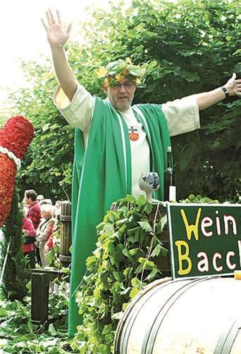 Hochzufrieden über seine Wettervorhersage grüßte Bacchus beim Festzug von seinem Prunkwagen das weinselige Völkchen