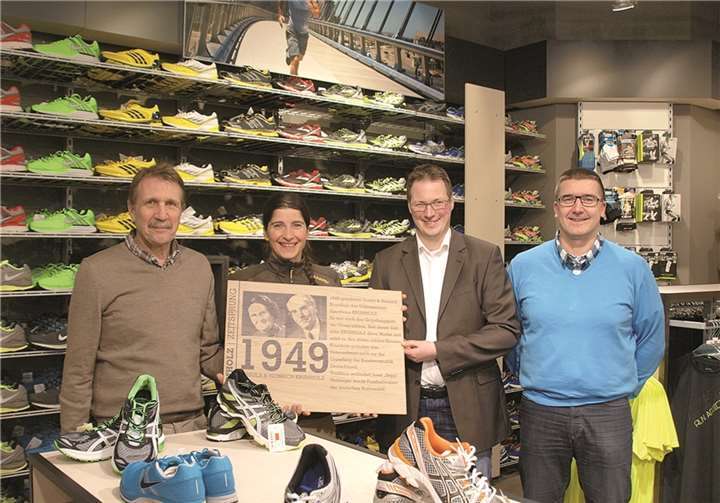 Holztafeln zeigen die markanten Meilensteine der Geschichte des Unternehmes, (v.l.) Paul Krumholz (Geschäftsführer), Kerstin Degen (Filialleiterin), Oliver Krumholz (Geschäftsführer) und Frank Bahr (Prokurist). US