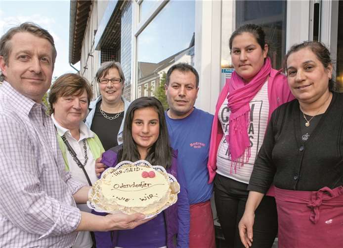 „Ihr seid Odendorfer wie wir“, steht auf der Torte, die der Ortsausschuss-Vorsitzende Jörg Freyer (links) zusammen mit Ortsvorsteherin Liselotte Kümpel und der Ersten Beigeordneten Petra Kalkbrenner der Familie Uzungelis als Zeichen der Solidarität überreichte. VJ