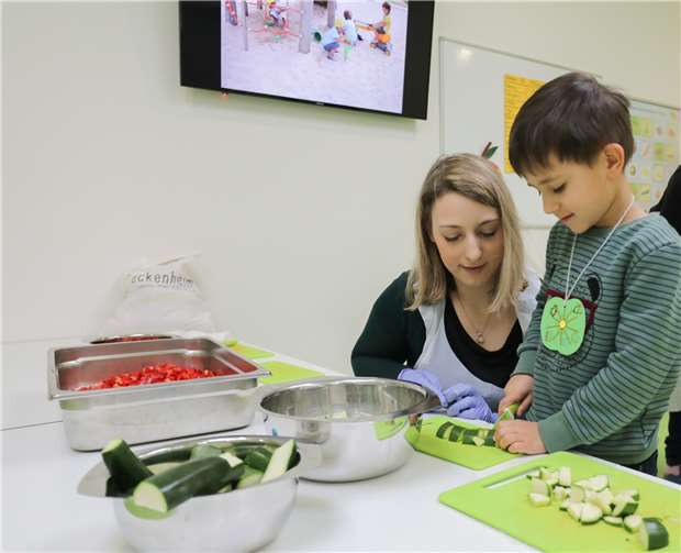 Ilias (5) schneidet mit Unterstützung der Erzieherin Melanie Hunsicker Zucchini.