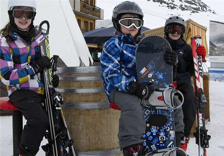 Ilka, Hendrik und Jakob warten vor dem Tipi auf ihre Ski- und Snowboardlehrer.