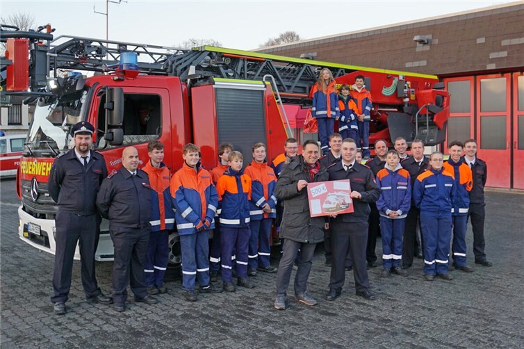 Im Beisein der Jugendfeuerwehr, der Jugendwarte und des Leiters der Freiwilligen Feuerwehr Fabian Althoff (links) übergibt Bürgermeister Sven Schnieber (vorne links) den Spendenscheck an Stadtjugendwart Sebastian Kesternich (vorne rechts). Foto: Freiwillige Feuerwehr Meckenheim