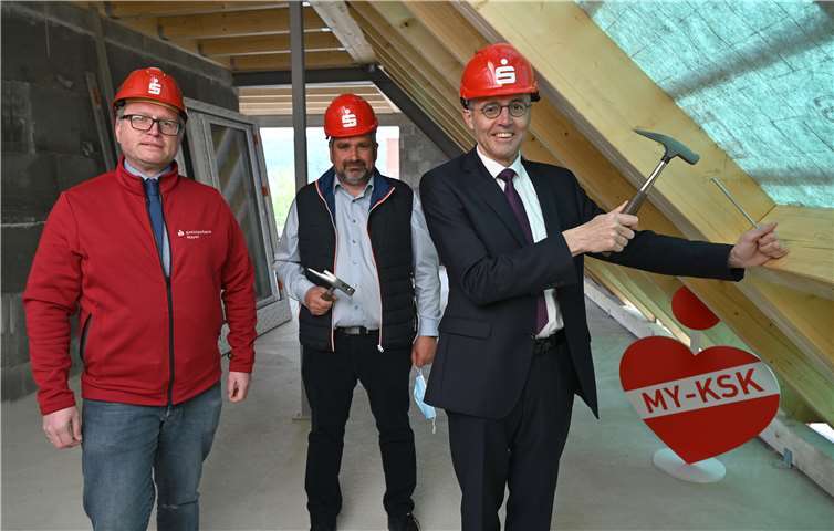 Im Beisein von Elmar Kanne (links) als Bauverantwortlicher der KSK Mayen sowie Verwaltungsratsmitglied Robert Ollig (mitte) setzt der KSK-Vorstandsvorsitzende Karl-Josef Esch (rechts) als Bauherr symbolisch den letzen Nagel im Dachstuhl an. Foto: KSK Mayen/ Ralph Künzel