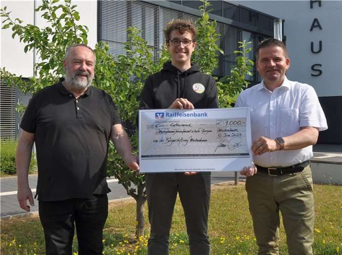 Im Beisein von Pfarrer Franz-Josef Steffl (links) übergibt der Vorsitzende des Stiftungsvorstandes der Bürgerstiftung, Bürgermeister Holger Jung (rechts), den Spendenscheck an Hanno Wurm (mitte) als Vertretung des Betreuungsteams der Meckenheimer Ferienfreizeit.  Foto: Bürgerstiftung Meckenheim