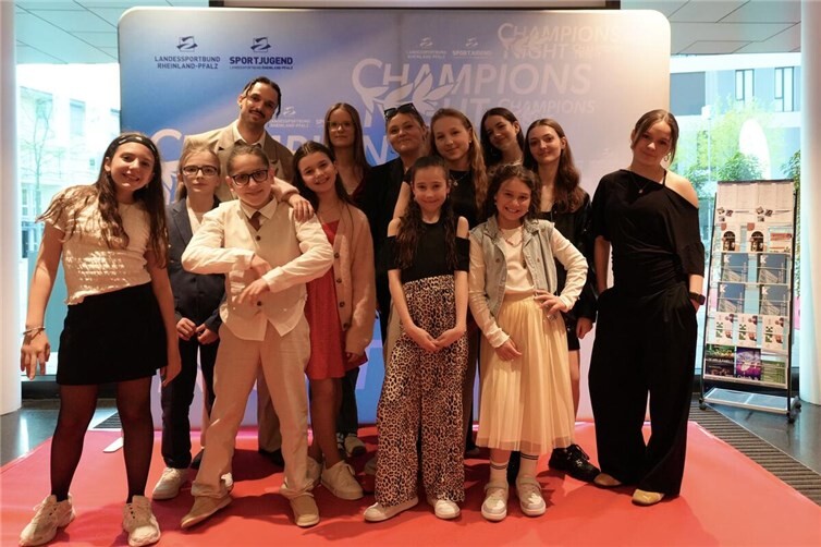 Im Foyer der Kultur- und Kongresshalle kING in Ingelheim stellen sich die ausgezeichneten Tänzerinnen und Tänzer mit ihrem Coach und Trainer Gabriel Hermes auf dem roten Teppich zu einem Erinnerungsfoto auf.