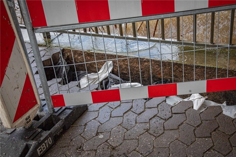 Im Gehweg am Peter-Altmeier-Ufer in Koblenz klafft ein Loch, das in Richtung Mosel provisorisch mit Sandsäcken abgedichtet wurde. 