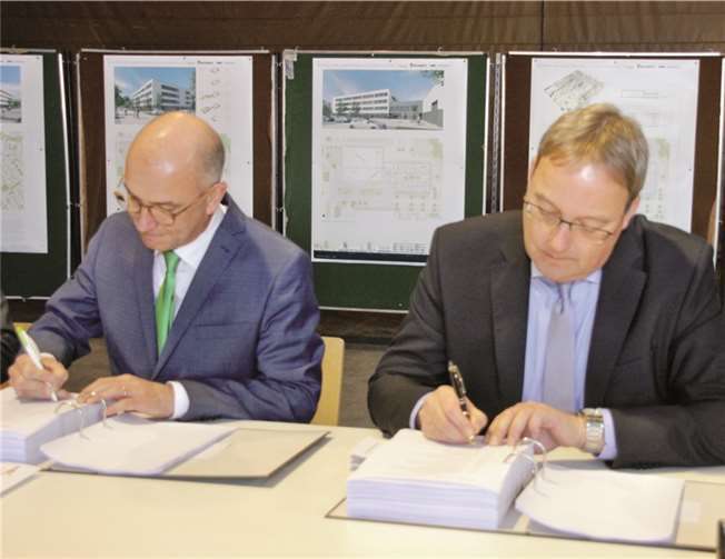 In der „alten“ Jungholzhalle wurde der Vertrag zur Beauftragung des Neubaus des Rathauses und der Jungholzhalle zwischen der Stadt und der Firma Goldbeck unterzeichnet. (Bürgermeister Bert Spilles, li., und Hans Walter Klein, Geschäftsführer Firma Goldbeck West GmbH).Stein
