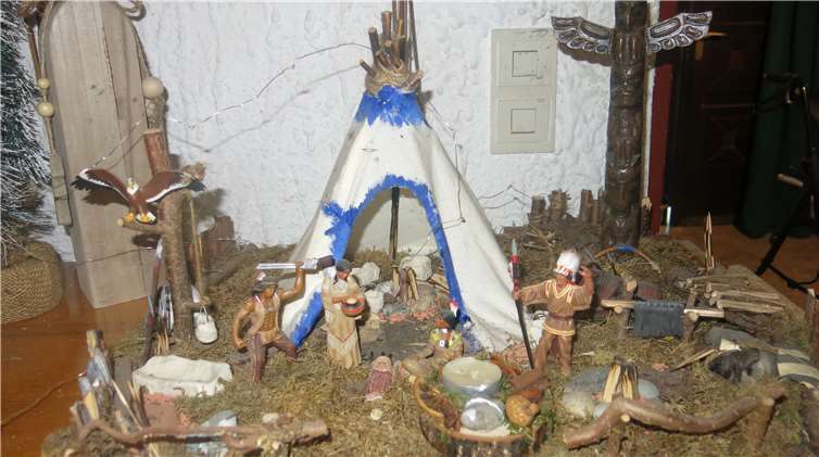 Indianisch: Vor dem Wigwam, geschützt durch einenTotem-Pfahl, betrachten die Indianer ihr Geschenk Gottes.