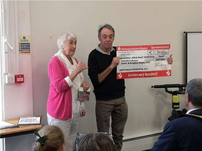 Inge Hempstead übergibt für den DEFK den Spendenscheck an Rob Oulton von What Next.