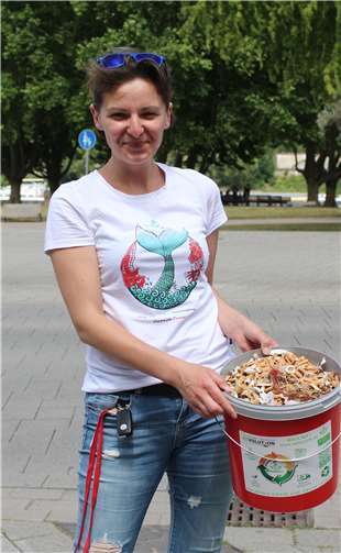 Initiatorin NAtalie Karij mit einem vollen Eimer Zigarettenstummel.