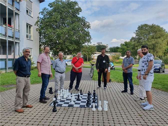 Iyad Asfour (2.v.li.) und Mario Seitz (5.v.li.) begrüßen immer dienstags ab 17 Uhr Interessierte zum Schach-Spielen vor dem Raiffeisenhof.Quelle: Quartiersmanagement Raiffeisenring