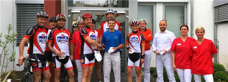 Jürgen Schütt, Dr. Uwe Siebert (Institut für Radiologie), Dr. Wilhelm Roth (Institut für Radiologie), Dr. Daniel Schmidtler (Institut für Radiologie) (Mitte) sowie Mitglieder des Praxisteams und der Radsportabteilung bei der Übergabe der Kleidungsstücke. privat