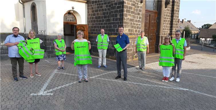 Jürgen Zinken (links) übergibt die Westen an einige Mitglieder des Begrüßungsdienstes. Foto: Elisabeth Schmitz