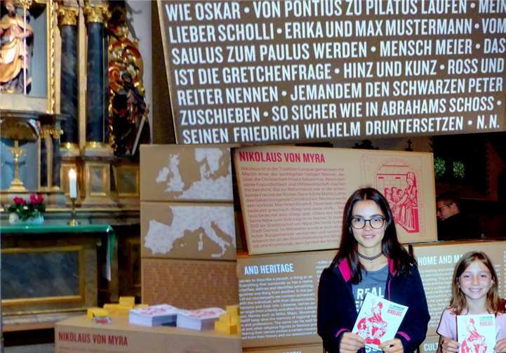 Julia und Viktoria werben zum Mitmachen bei der Namensforschung, die sich auch in Redewendungen widerspiegelt.