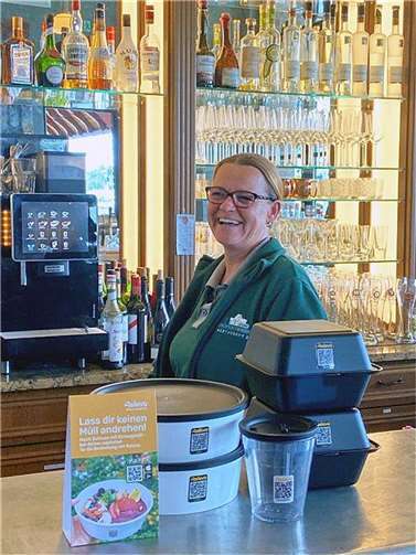 Katja Coraluzzo vom Stellwerk Meckenheim präsentiert das smarte pfandfreie Mehrwegsystem für Speisen und Getränke zum Mitnehmen und Liefern. Quelle: Stadt Meckenheim