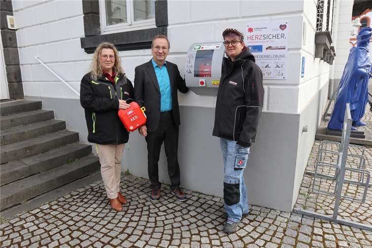 Kerstin Wagner (l.) und Missy Motown (r.) vom Helfer-Stab mit Bürgermeister Andreas Geron vor dem neuen Defibrillator am Sinziger Rathaus.  Foto: Stadtverwaltung Sinzig