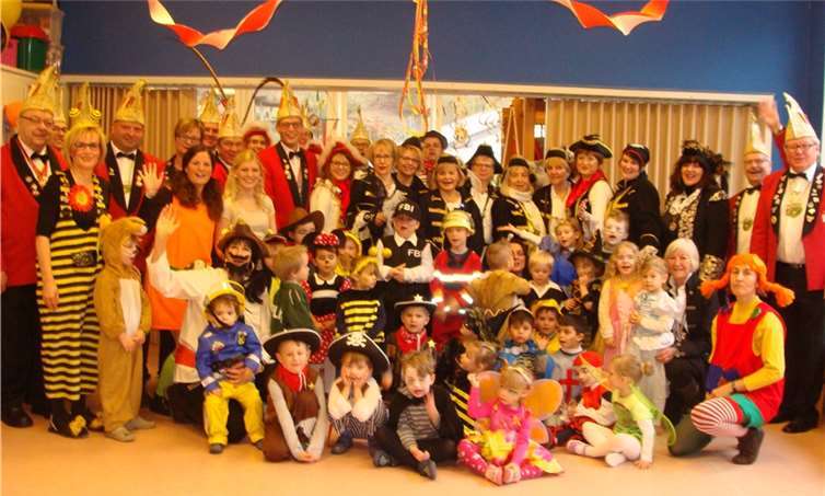 Kinder, Erzieherinnen, Karnevalisten und Möhnen stellen sich zum Gruppenbild auf.