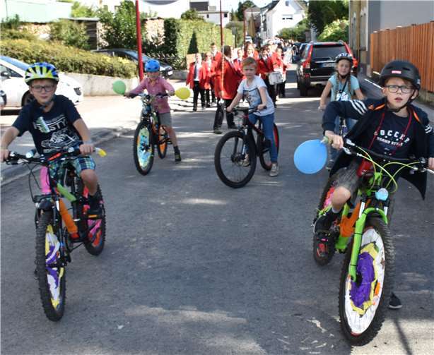 Kinder auf bunt geschmückten Fahrrädern an der Spitze des Festumzugs.