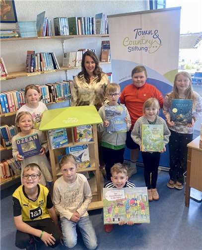 Kinder der Astrid Lindgren Grundschule in Herschbach werden durch die Town & Country Stiftung mit einem Bücherhaus inklusive Wasserbücher gefördert. Stiftungsbotschafterin Janina Corzilius übergab die Förderung bei einem Besuch in der Schulbücherei. Foto: Grundschule Herschbach
