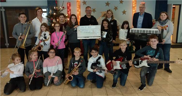 Kinder der Rockklasse 6a und Bläserklasse 5a, Klassenleiterin Kerstin Gelhard (hintere Reihe, 2. v. .), Tom Theisen (Bildmitte, mit Scheck), Klassenleiterin Barbara Daubländer (hinten, 4. v. r.), Schulleiter Gerhard Müller (hinten, 2. v. r.).Foto: privat