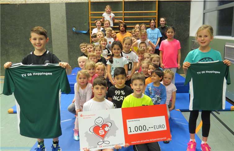 Kinder mit dem Spendenscheck und zwei Muster-T-Shirts. Privat