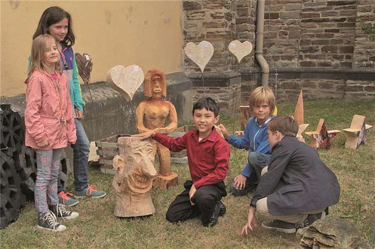 Kinder mit einigen der kunstvoll gefertigten Holzfiguren.