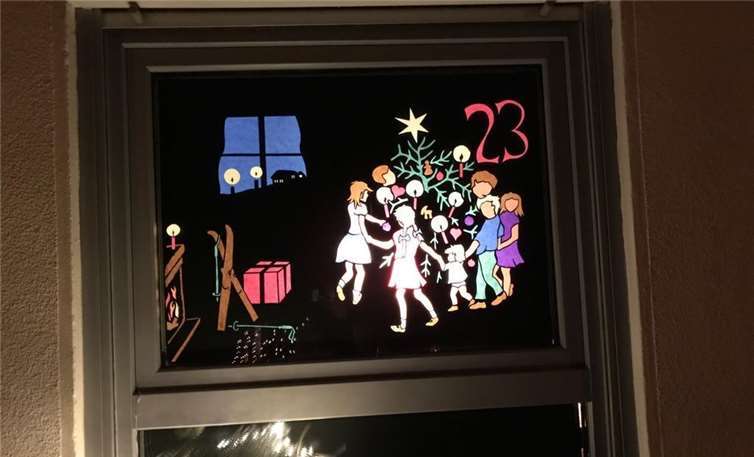 Kinder tanzen um den Weihnachtsbaum.