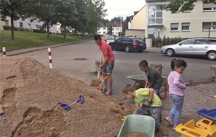 Kinder und Erzieher schaufeln gemeinsam Sand. privat