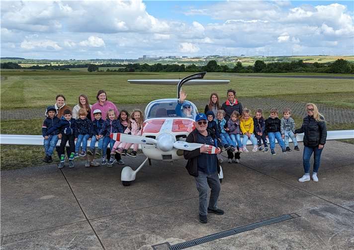 Kinder und Erzieherinnen am vereinseigenen Motorsegler Grob G109B. Mit auf dem Foto sind die LSV-Piloten Richard Flohr-Swann (am Propeller) und Schatzmeister Wolfgang Graef (im Cockpit).  Foto: privat