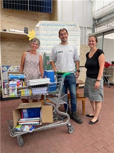 Kirsten Becker (rechts, WJ Bonn) und Dimi Mpoulis (Mitte, TINKS) übergeben Schulmaterialien der Aktion „Kauf1Mehr“ an Andrea Neu.  Foto: Wirtschaftsjunioren Bonn/Rhein-Sieg